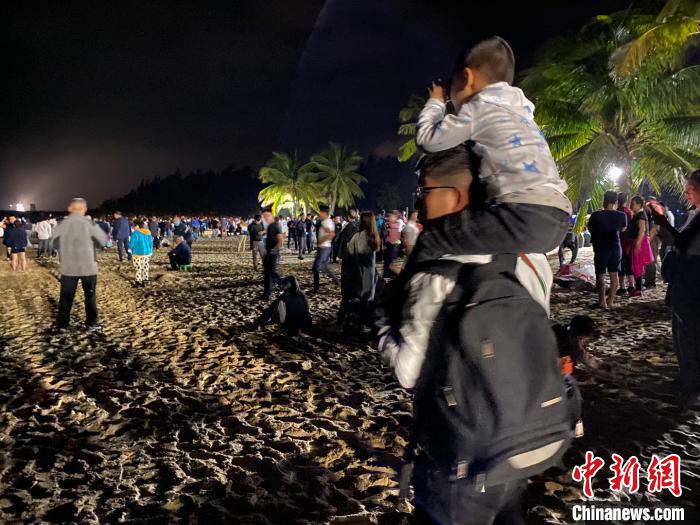 一位兒童坐著父親的肩上用望遠(yuǎn)鏡觀看文昌航天發(fā)射場。凌楠 攝