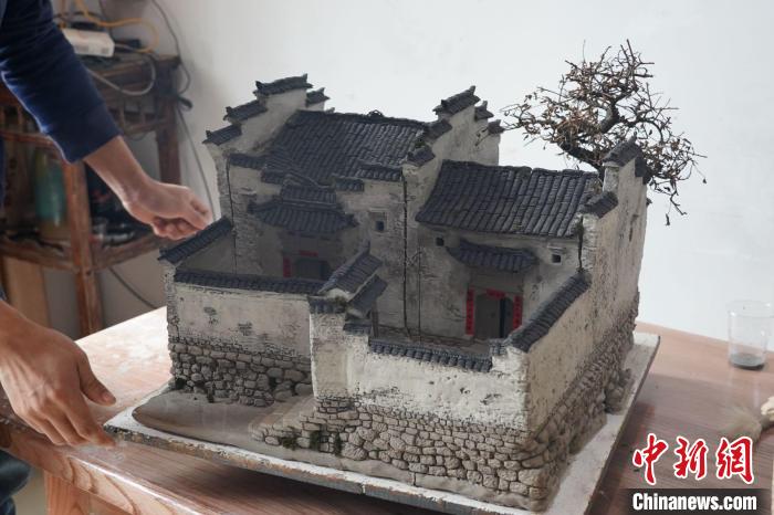 圖為黃簡(jiǎn)松完工的一件陶土民居作品 蒲文思 攝