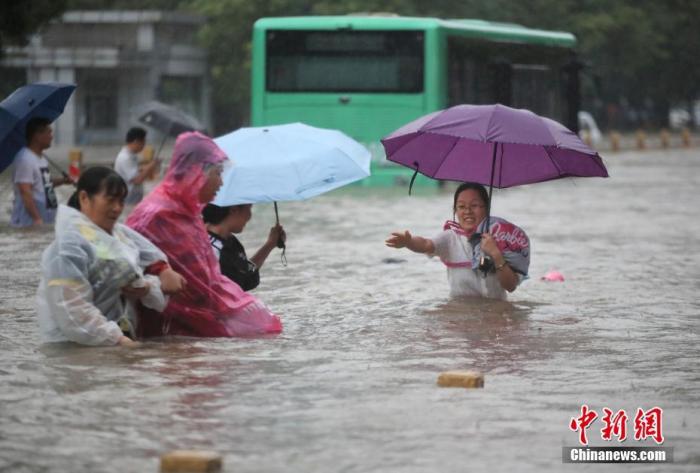 7月20日，鄭州遭遇強降雨，在經(jīng)三路、農業(yè)路上，市民互相幫助走在齊腰深的積水里。 圖片來源：視覺中國